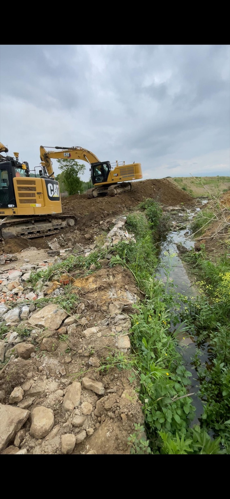 Excavators reshaping a riverbank during hydraulic earthworks